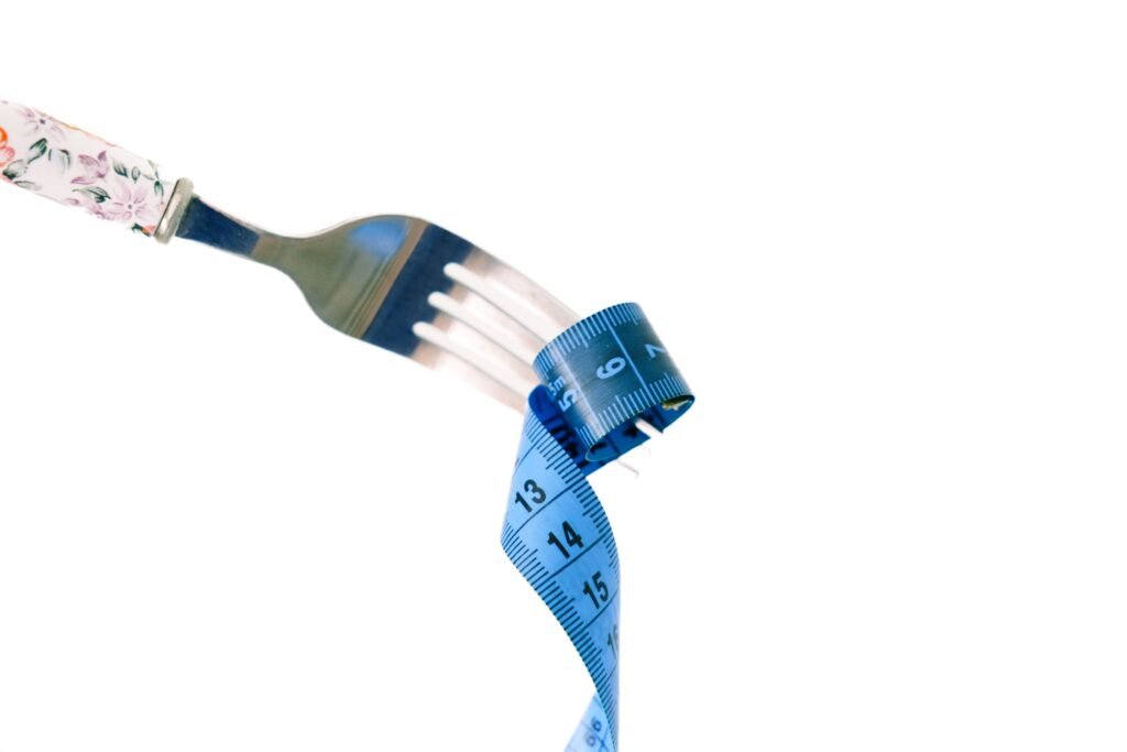 Fork twirling a blue measuring tape, symbolizing diet planning steps