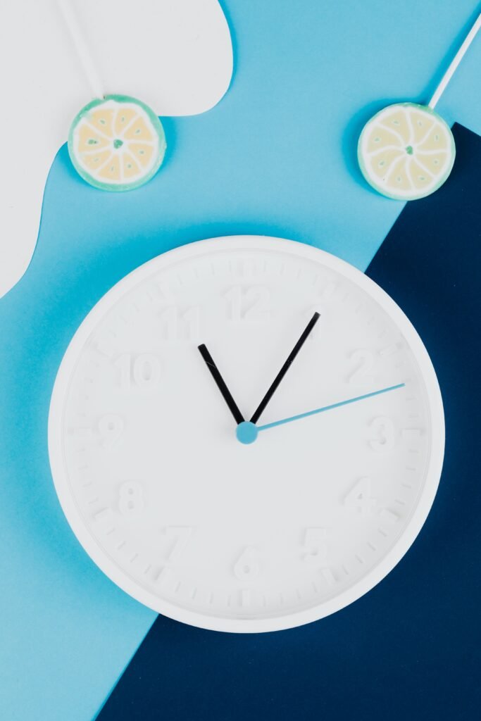 White clock with lemon lollipops on a blue background, representing the 16:8 fasting window
