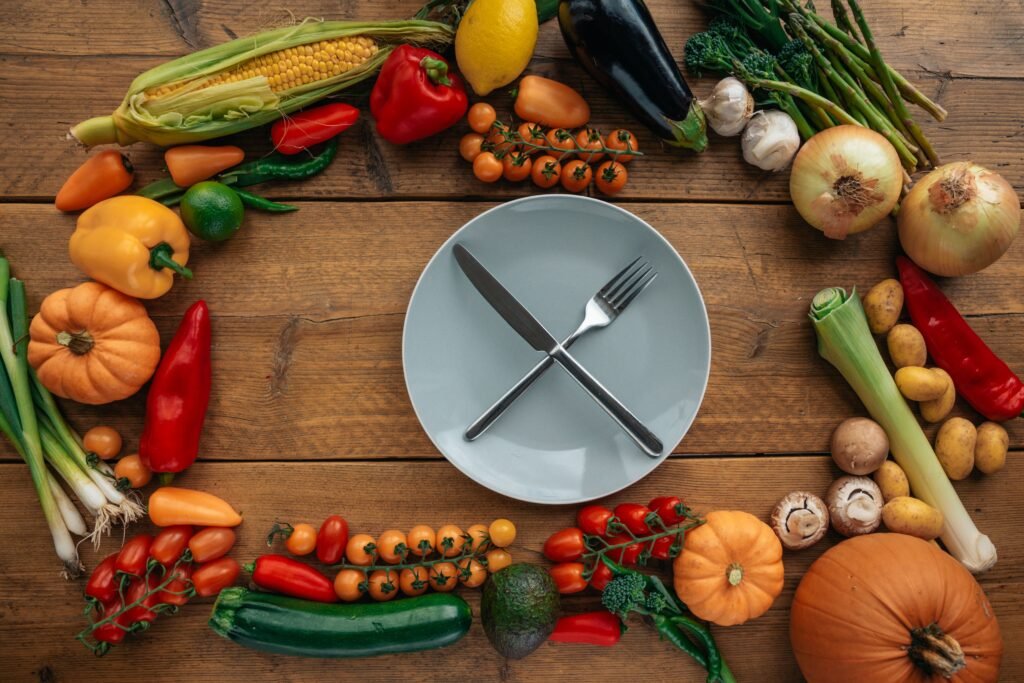 Fresh vegetables arranged around an empty plate, symbolizing a fasting reset