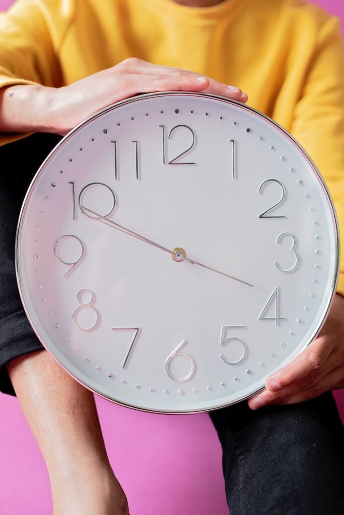 Person holding a large analog wall clock, symbolizing time-restricted eating